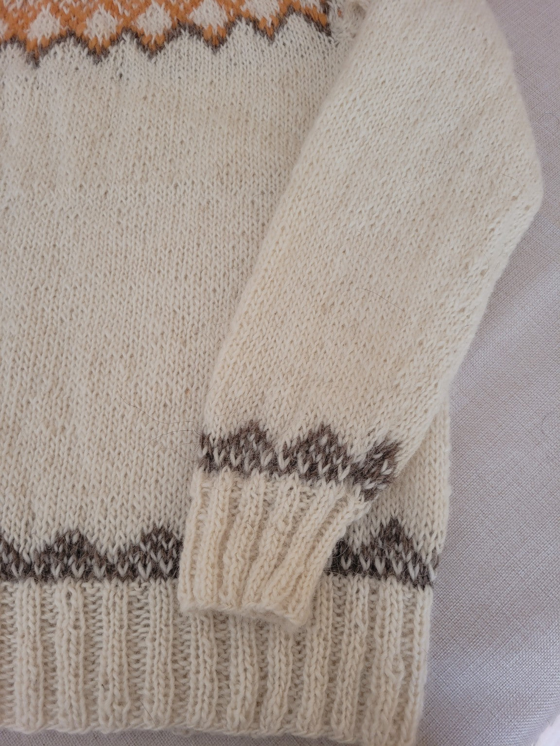 Detailaufnahme des Ärmelbündchens und Saummusters des handgestrickten Islandpullovers Alfheidur Winter Light.