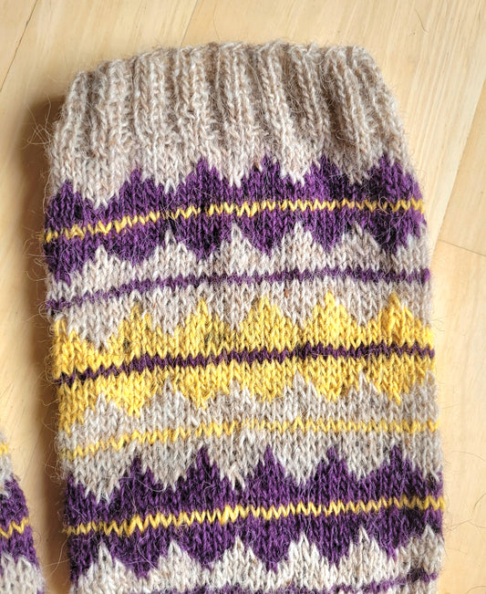 Detailaufnahme des gestrickten Musters in Senfgelb und Lila auf naturfarbener isländischer Wolle