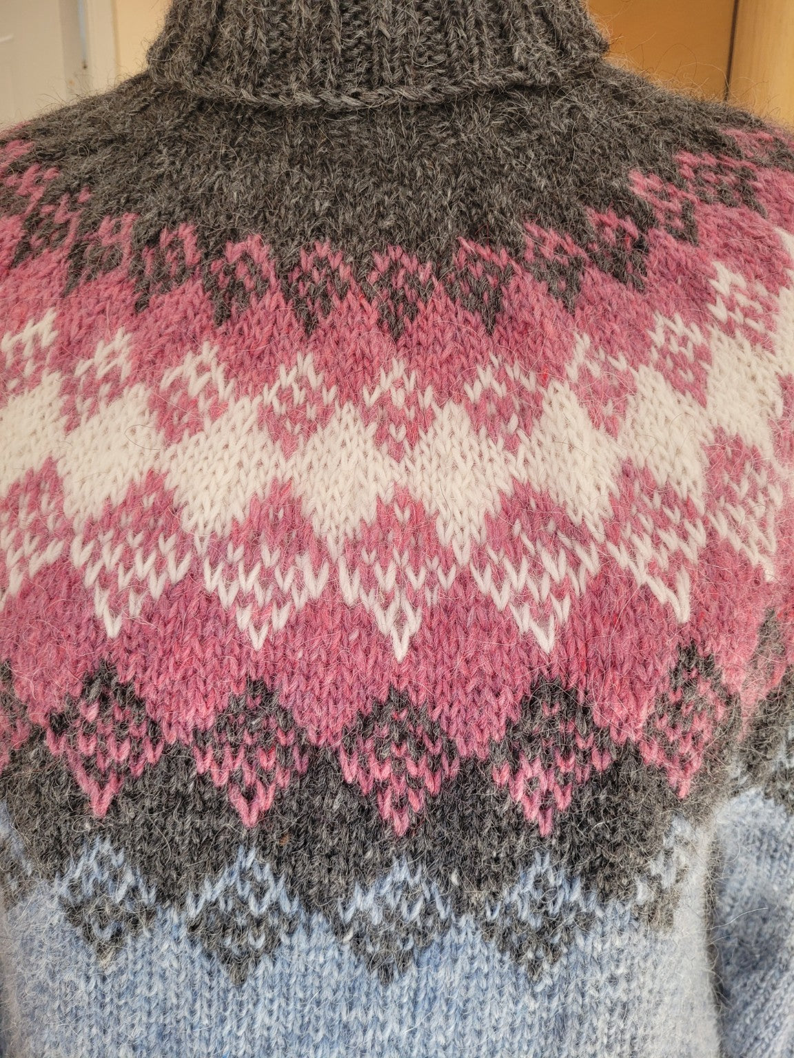 Detail des handgestrickten Islandpullovers Hiutaleneule aus Islandwolle mit traditionellem isländischem Muster und strukturierter Wolloberfläche.