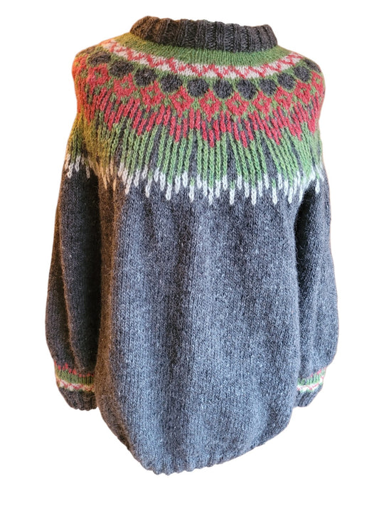 Handgestrickter Islandpullover „Hopi“ aus isländischer Léttlopi-Wolle in Anthrazit mit Rundpassenmuster in Grün, Rot und Naturweiß.