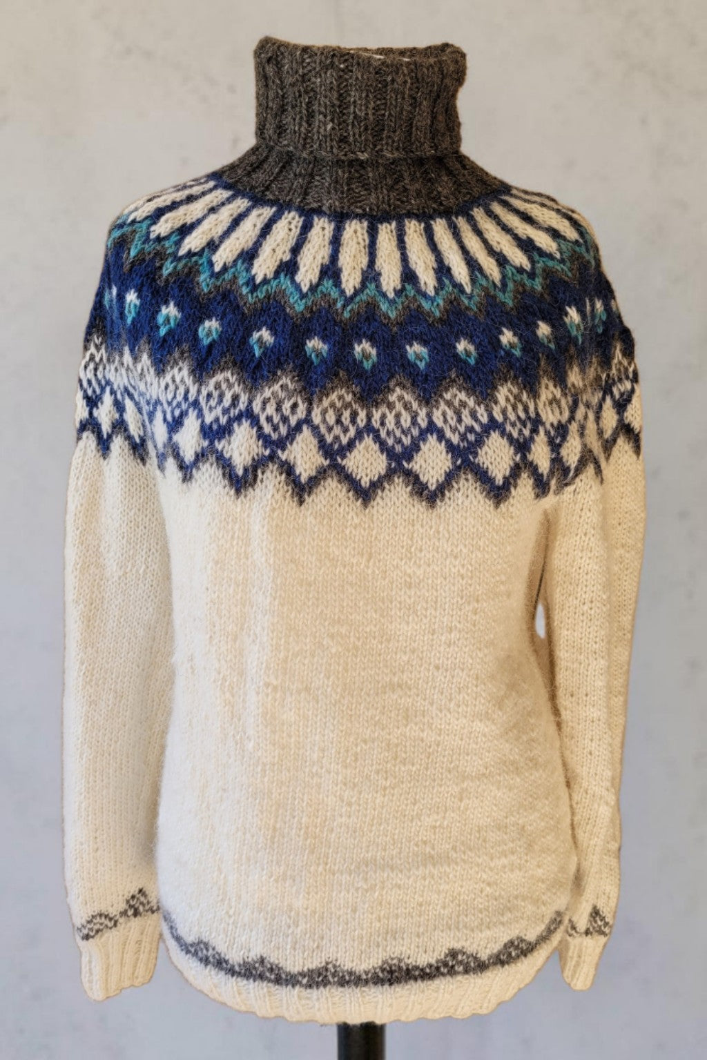 Handgestrickter Islandpullover Alfheidur Nordic Sea Größe M aus Lettlopi mit Rundpasse in Blau, Petrol und Grau auf Puppe