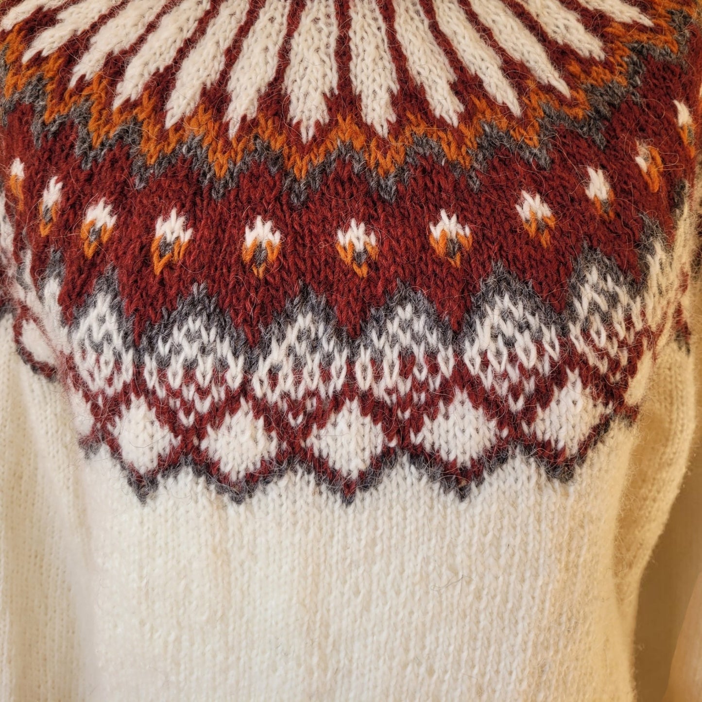 Detail der Rundpasse vom handgestrickten Islandpullover Alfheidur mit traditionellem Muster in Bordeaux, Grau und Naturweiß