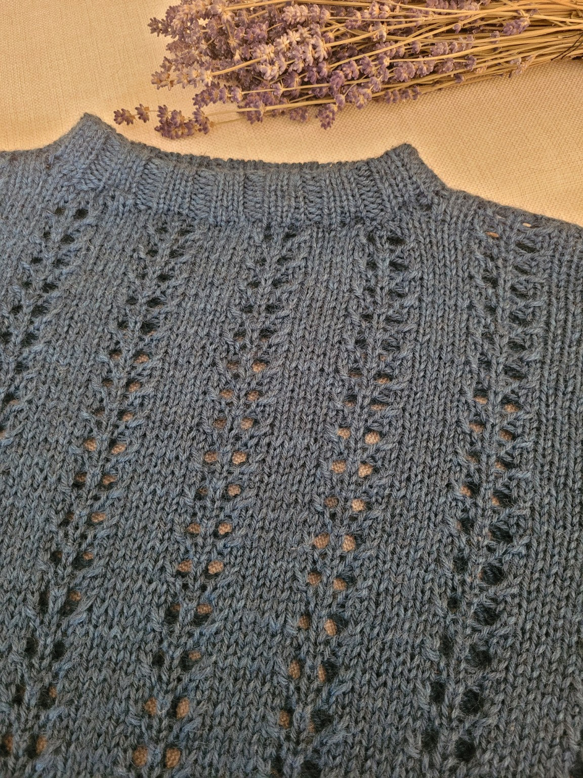 Detailaufnahme des handgestrickten Damenpullovers BFL Nele aus Bluefaced-Leicester-Wolle mit feinem Lochmuster und geripptem Rundhalsausschnitt.