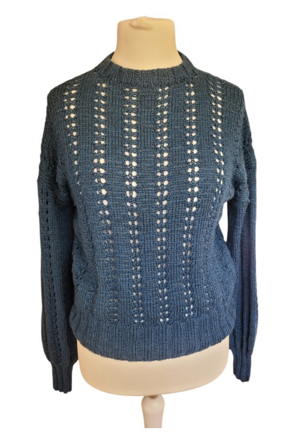 Handgestrickter Damenpullover BFL Nele aus Bluefaced-Leicester-Wolle mit feinem Lochmuster, voluminösen Ärmeln und gerippten Bündchen auf einer Schneiderpuppe.