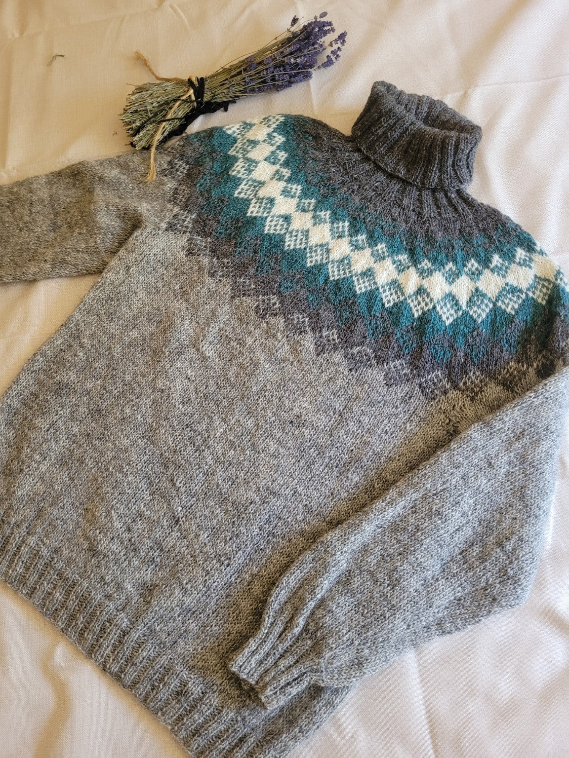 Handgestrickter Islandpullover „Nordic Sea“ aus isländischer Lettlopi-Wolle in Grau, Petrol und Naturweiß mit traditioneller Rundpasse und Rollkragen.