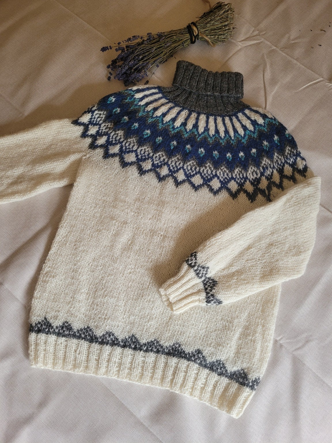 Handgestrickter Islandpullover aus isländischer Lettlopi-Wolle in Naturweiß, Dunkelblau, Türkis und Anthrazit mit traditioneller Rundpasse.