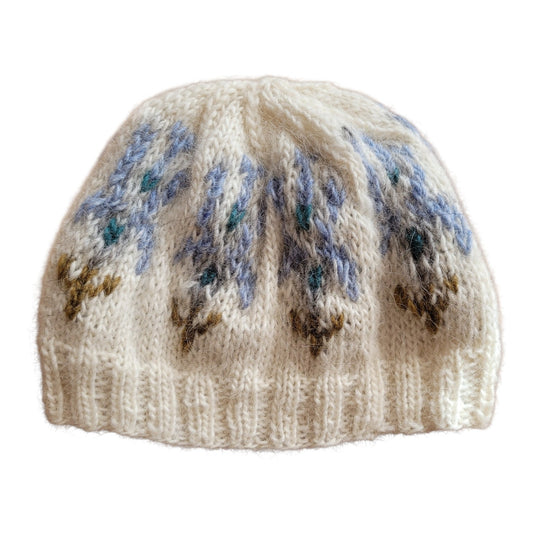 Handgestrickte Islandmütze Ískaldur aus Islandwolle in Naturweiß mit eisblauem Jacquardmuster und petrolfarbenen Akzenten.