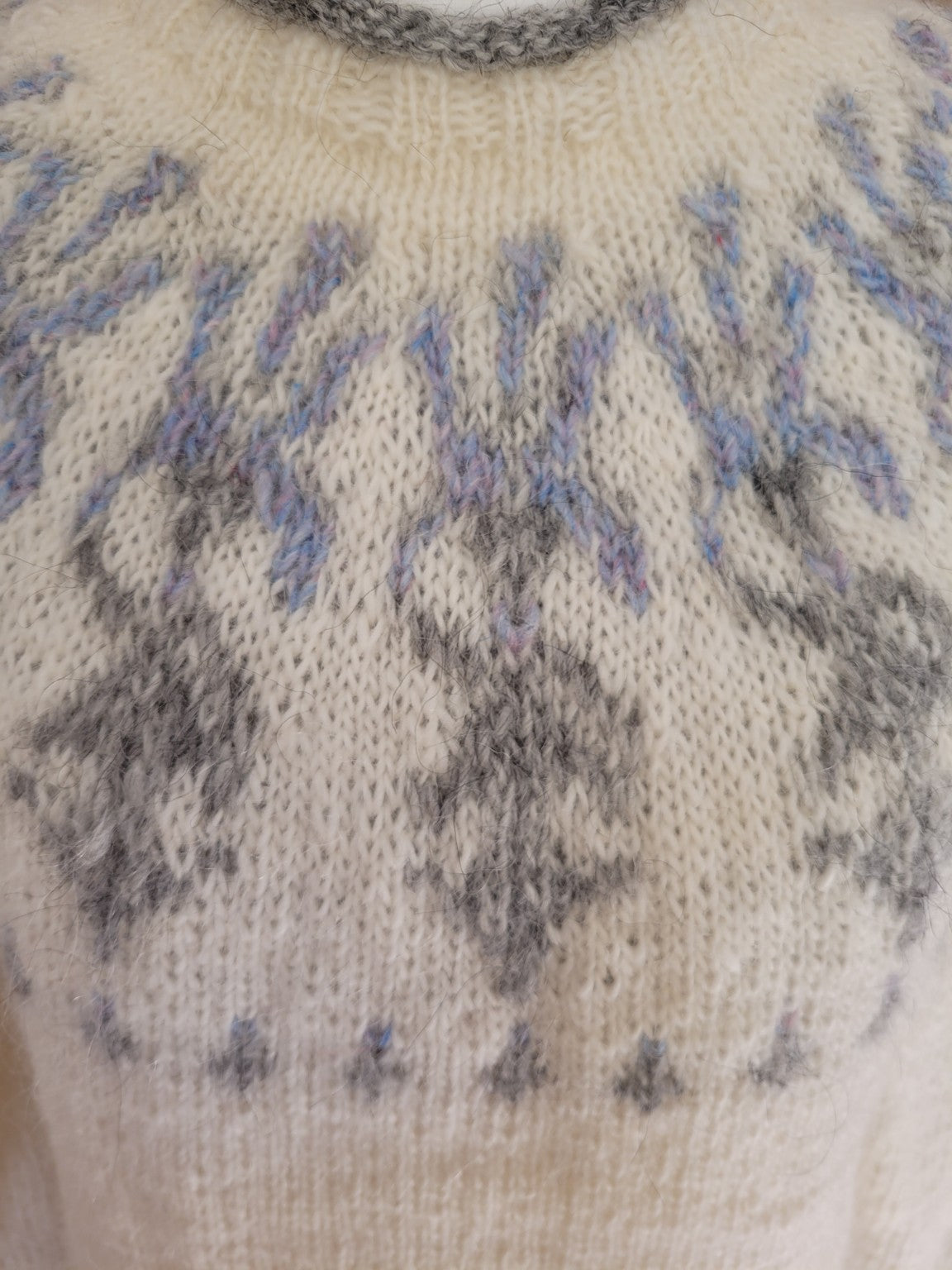 Detailaufnahme der Passe des handgestrickten Islandpullovers Ískaldur in Winter Light mit filigranem Eisblumenmuster aus Hellgrau, Silbergrau und Milky Way auf heller Léttlopi-Wolle.