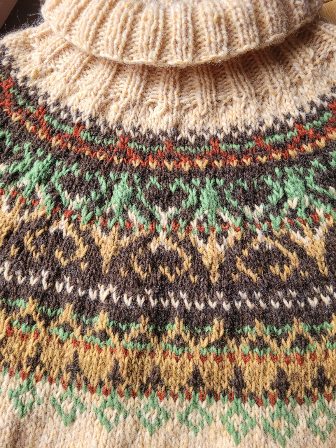 Nahaufnahme der Rundpasse des handgestrickten Islandpullovers Alasuq mit traditionellem nordischem Muster in erdigen Naturtönen.