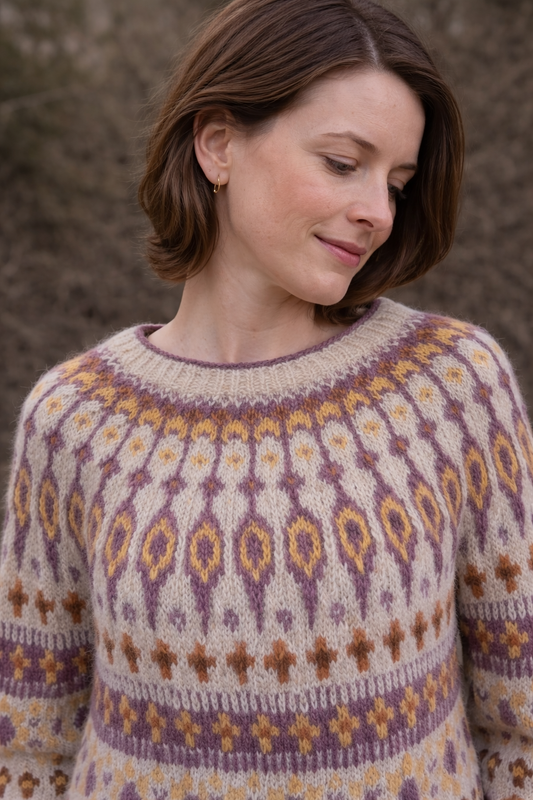 Frau trägt handgestrickten Islandpullover Katmandu Nr. 2 aus Lettlopi Wolle in Größe L mit nordischem Muster in Creme, Lila und Senfgelb – Maschenhexe Unikat